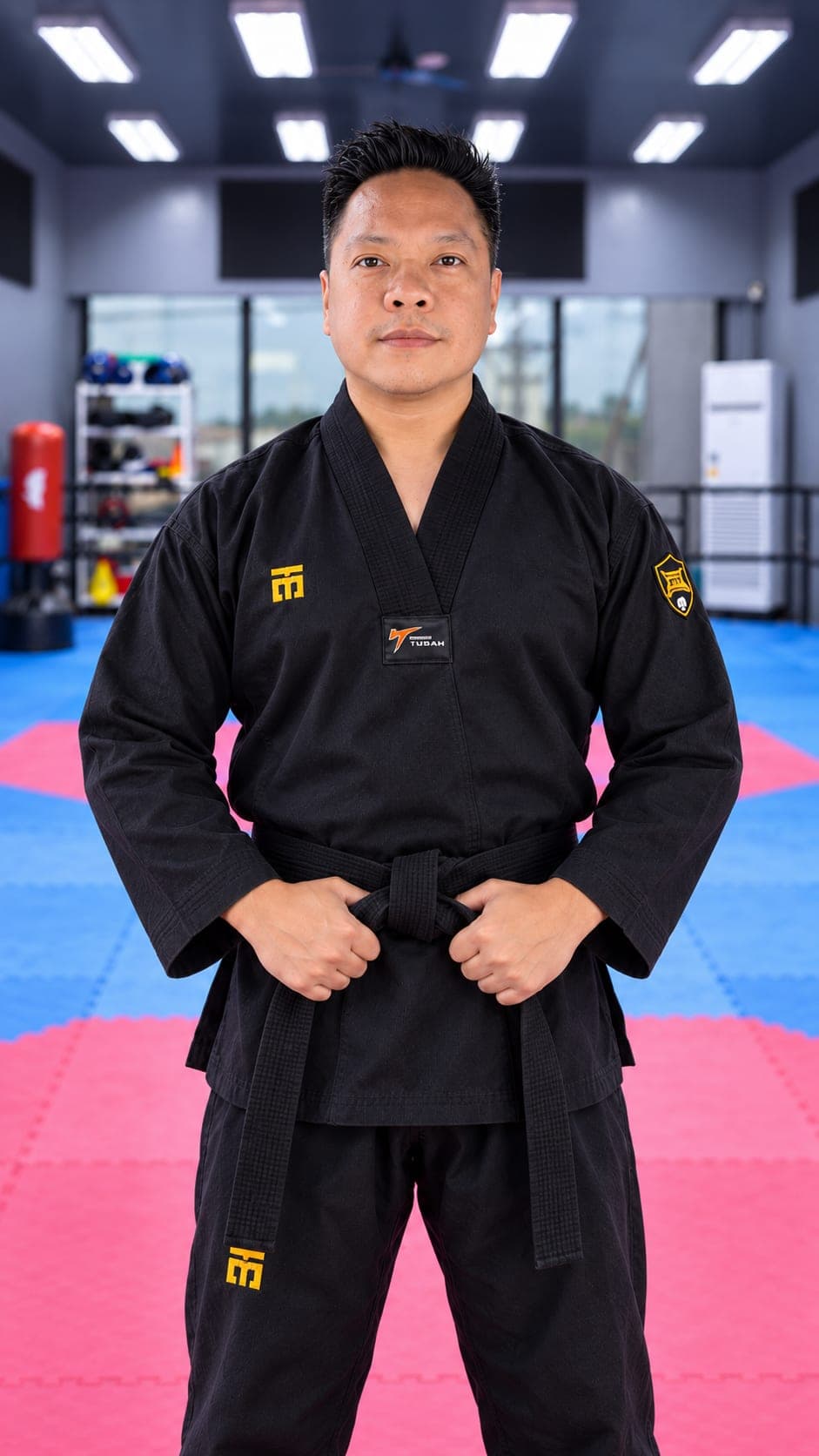 Sabumnim Wilt Valencia in a black dobok and black belt, standing in the WVT training hall.