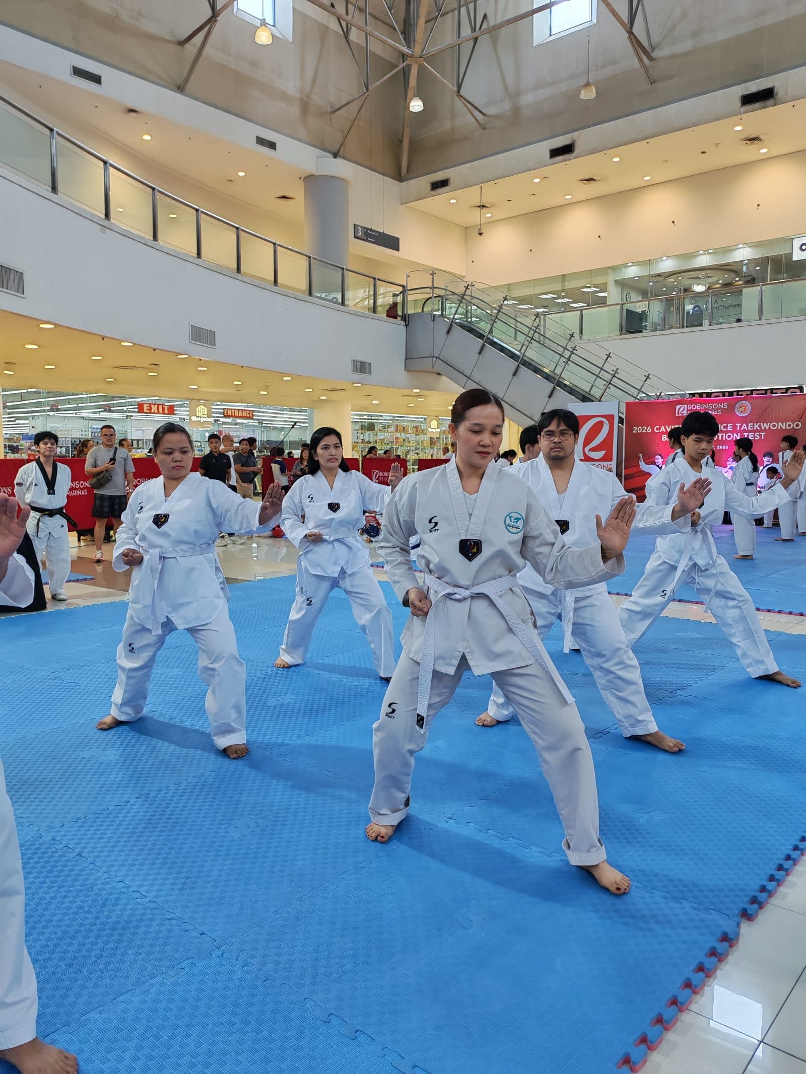 WVT students performing poomsae on blue mats at a mall.