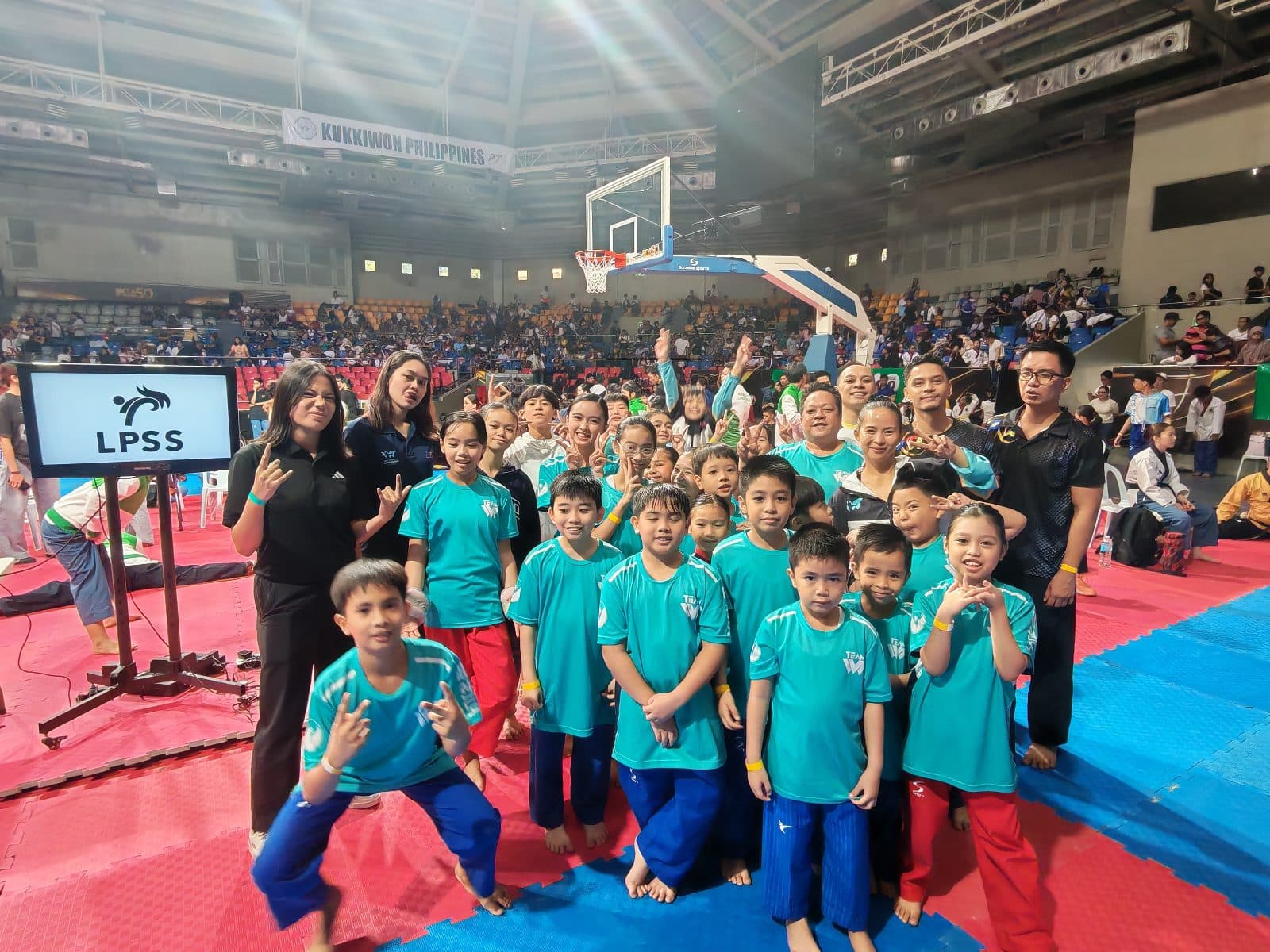 WVT athletes in matching teal shirts with their coaches at a tournament venue.